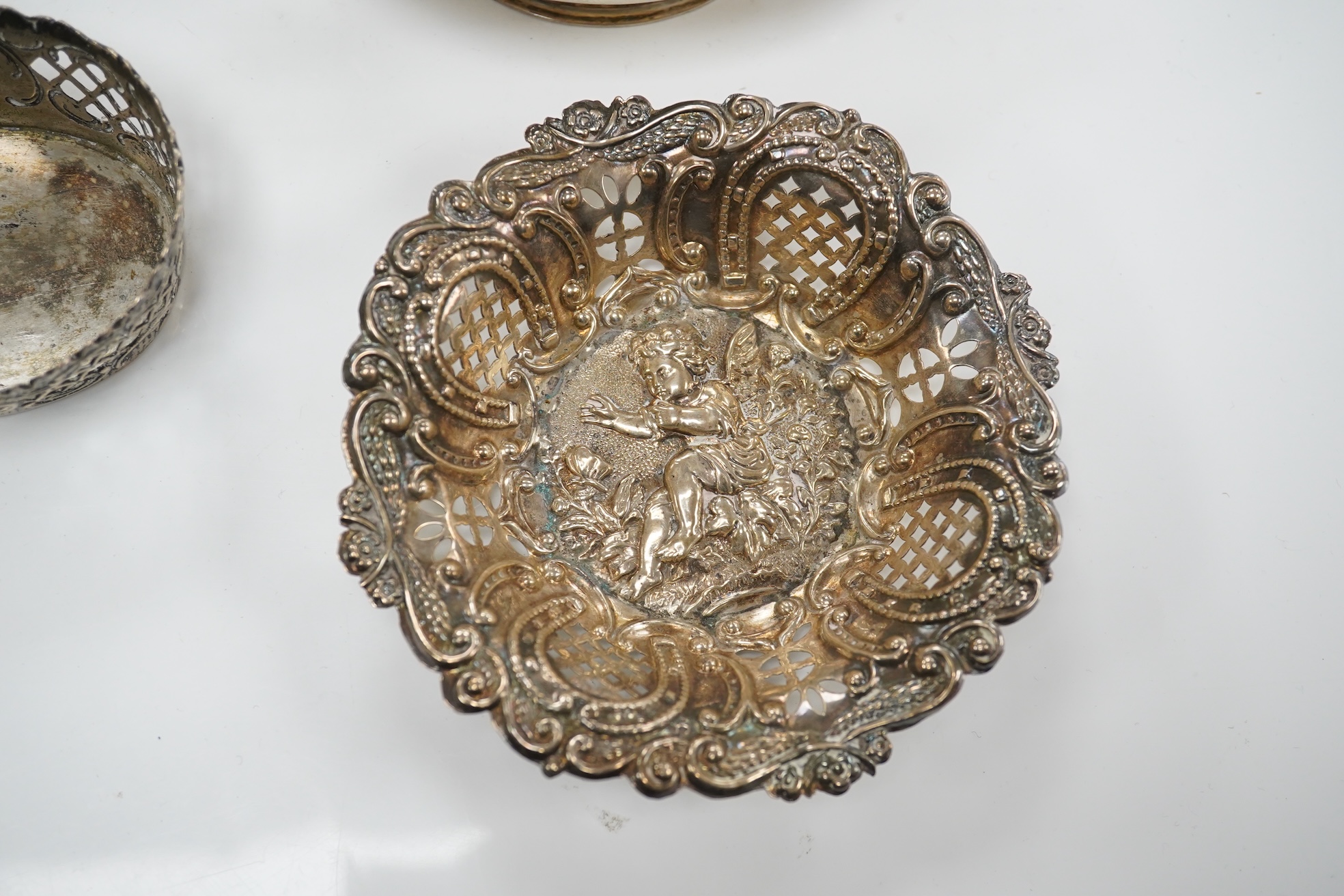 A pair of Edwardian pierced white metal dishes embossed with cherubs, a pair of two handled silver oval bowls, Birmingham, 1936 and two small baskets, one silver one 800 standard. Condition - poor to fair